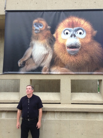 Joel Sartore posing with one of his posters on campus that was defaced with "googly eyes." Photo Courtesy of Evan Sgouris